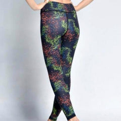 A woman in iYoga's CONSTELLATION LEGGING, which feature a black and green pattern.
