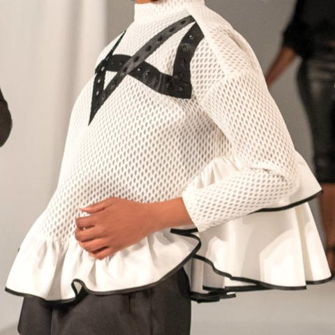 A woman in a Nik Spruill Crossroads Top and black pants.