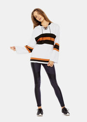 A woman in black leggings and a white FABE LACED TOP by The Upside.