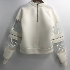 A white Nik Spruill FELICITY CONVERTIBLE TOP sweatshirt with clear sleeves hanging on a wall.
