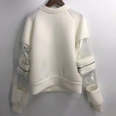 A white Nik Spruill Felicity Convertible Top with clear sleeves hanging on a hanger.