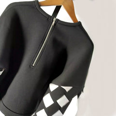 A Nik Spruill Stitch crochet fringed top hanging on a wooden hanger.