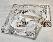A Nik Spruill FROSTY glass dish with a metal handle on a white surface.